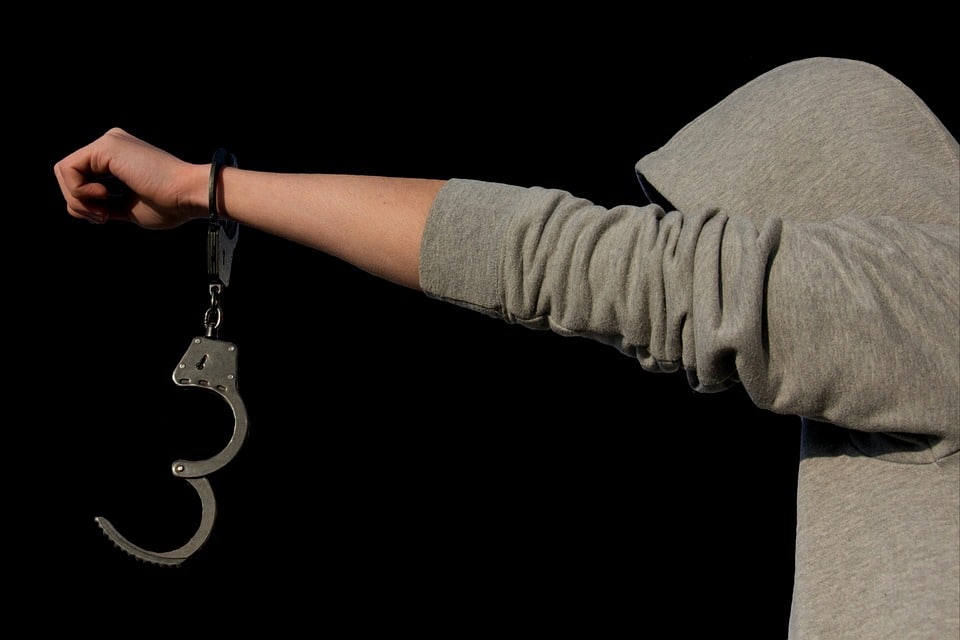 man in hoodie with one hand cuffed