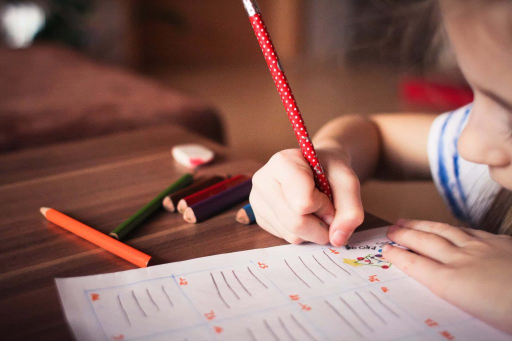 child writing with polkadot pencil