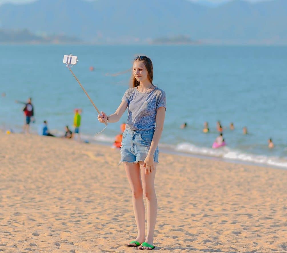 girl at beach with selfie stick