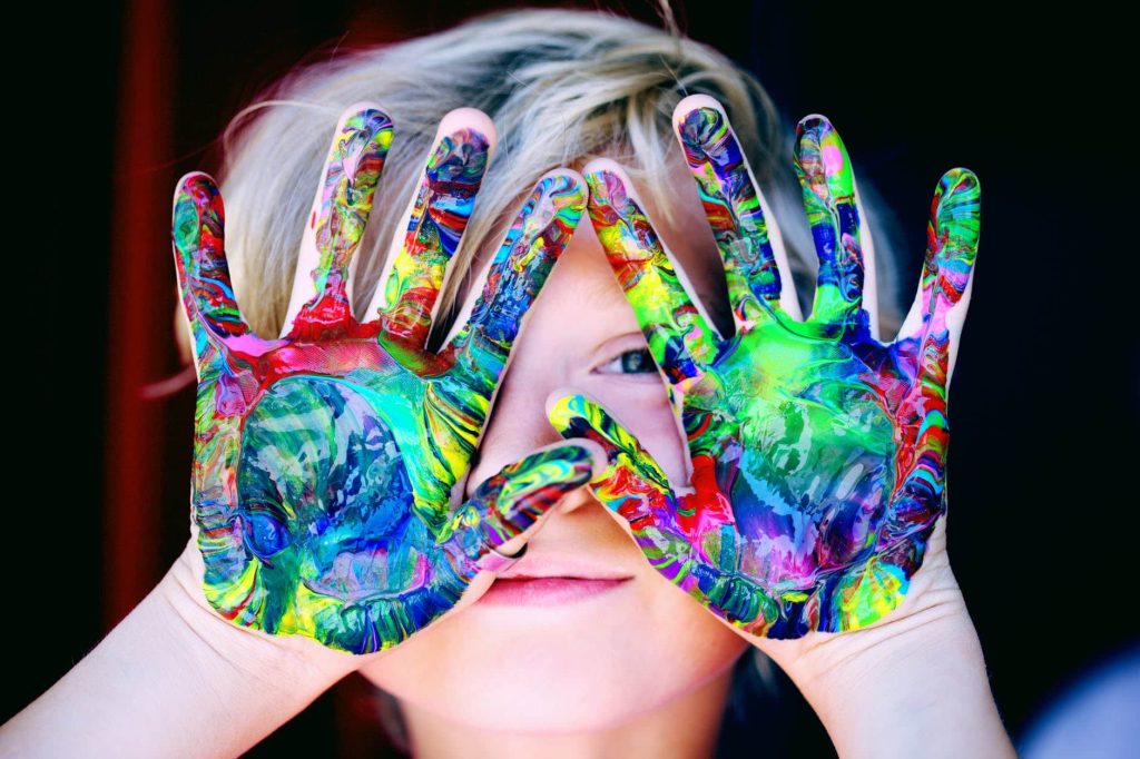 child with colorful paint on hands