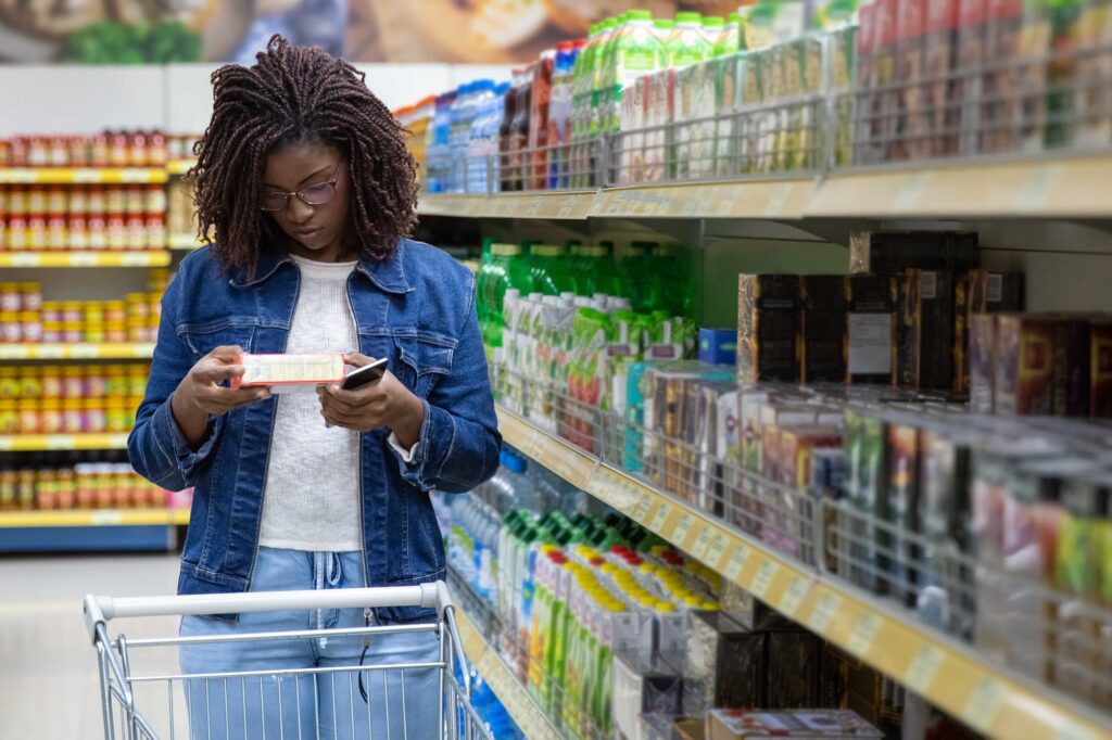 woman looking at list in a grocery store with cart in front of her