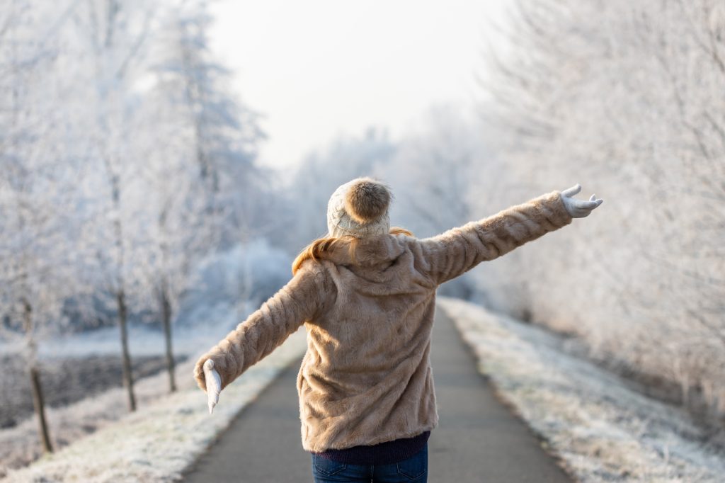 Happy woman enjoying fresh air during walk in winter nature.